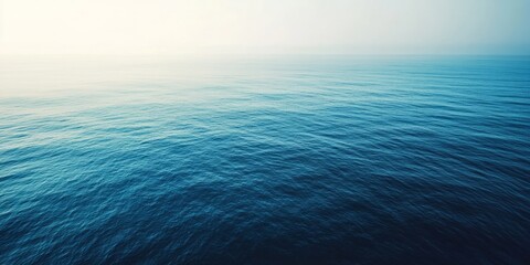 Obraz premium Aerial View of Calm Blue Ocean Waters, Showcasing the Tranquil Gradient from Deep Blue to Turquoise. A Serene and Expansive Scene that Captures the Peaceful Beauty of the Sea, Ideal for Nature, Travel