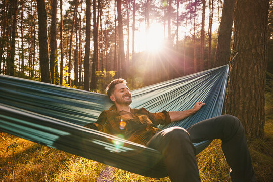 Relaxed man resting in a hammock in forest during autumn sunset