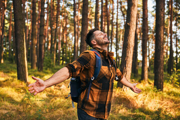 Happy man embraces forest nature during autumn hike