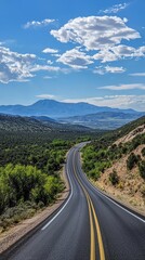 A Winding Road Through Rolling Hills, Leading to a Distant Mountain Range Under a Blue Sky