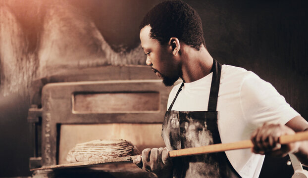 Baker, bread and black man with oven, chef and confidence with small business, dough and healthy. African person, hobby and employee with nutrition, skills and talent with food, wheat and kitchen - Powered by Adobe
