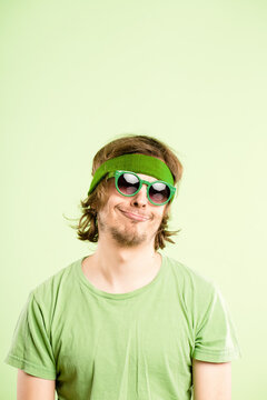 Thinking, sunglasses and face of man in studio with funny, comic or goofy facial expression. Thoughtful, comedy and portrait of crazy male model with silly personality isolated on green background