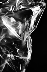 plastic wrap, cellophane, ripped and crumpled against a black background