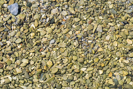Photo background texture, rocky river bottom with clear transparent water on the shallows.