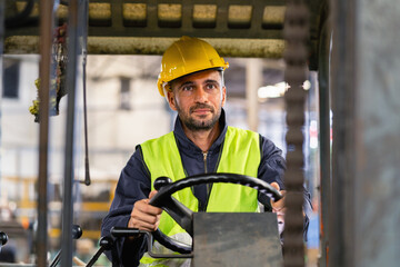 man in a yellow helmet and a green vest is driving a forklift
