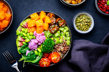 Vegan vegetarian buddha bowl with pumpkin, quinoa, tomatoes, spinach, celery, edamame, tofu, broccoli and seeds, black background, top view