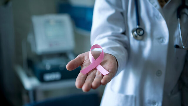 The medical professional is adorned with a pink ribbon, symbolizing breast cancer awareness, in a professional and cinematic setting, surrounded by medical equipment and soft lighting.