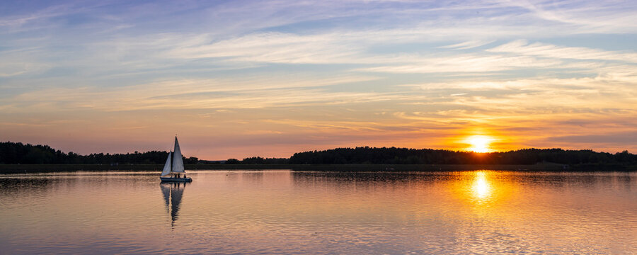 Panoramic summer landscape of Lake Rothsee with sailing boat during sunset near Nuremberg in Bavaria in Germany