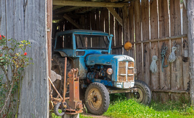 Old blue tractor in a wooden garage in a rural area © EMILIA