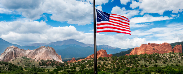 Beautiful view of Garden of the Gods in Colorado Springs with a new colorful  American Flag flying high above the stone formation and Pikes Peak In the distance.