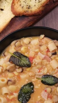 video verticale, zuppa di cicerchie con pasta salvia e pane tostato, tagliere con fette di pane tostato