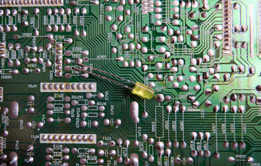 A yellow led on the soldered layer of an electronic circuit board.