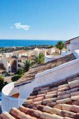 Fototapeta premium Building, rooftop and tiles with landscape, architecture and blue sky for travel with aesthetic. Culture, heritage and terracotta with sustainability, insulation or eco friendly clay roof in Spain