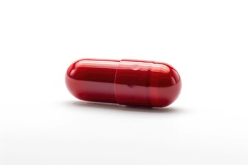 A single red pill sits on a plain white surface, ready for use