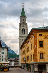 Fototapeta premium A view of the iconic church tower in the heart of Cortina d'Ampezzo. The architectural beauty of the tower stands tall against the backdrop of the surrounding Alpine scenery