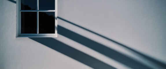 Obraz premium Window casting long shadows on smooth wall, showcasing modern minimalistic design with emphasis on light and space, perfect for interior decor themes.