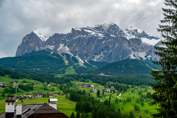 A panoramic view of the picturesque town of Cortina d'Ampezzo, nestled in the heart of the Dolomites. Majestic mountains rise in the background, offering a stunning natural backdrop.