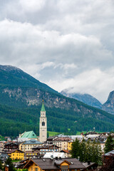 A panoramic view of the picturesque town of Cortina d'Ampezzo, nestled in the heart of the Dolomites. Majestic mountains rise in the background, offering a stunning natural backdrop.