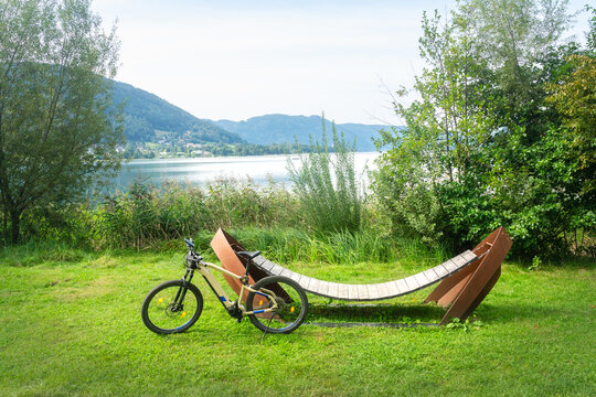 Fahrrad lehnt an einer Liege aus Holz im Bleist&auml;tter Moor Landschaftsschutzgebiet in Steindorf am Ossiacher See in Villach in K&auml;rnten &Ouml;sterreich