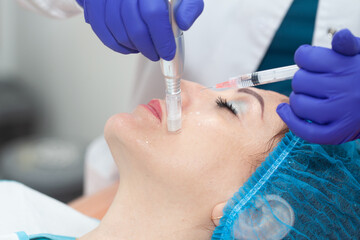 Naklejka premium Application of an anti-aging facial rejuvenation cocktail using micro needles. Dermatology concept. Aesthetic medicine concept.