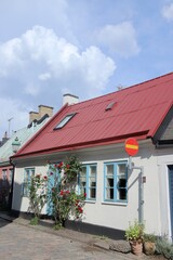 Scandinavian Summer House with Red Roof and Roses on a Sunny Cobblestone Street