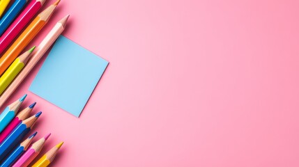 A vibrant collection of colored pencils arranged against a pink background with a blank blue note paper, perfect for back-to-school, creativity, and education.