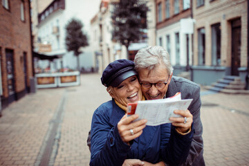 Senior couple laughing and exploring city with a map