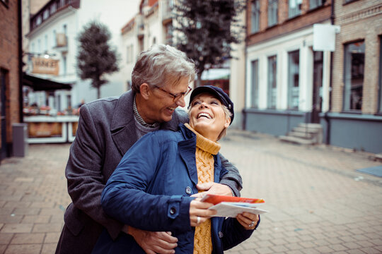 Senior couple laughing and exploring city with a map