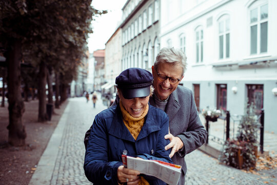 Senior couple laughing and exploring city with a map