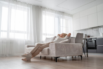 A senior woman is enjoying a peaceful moment while relaxing on a sofa at her home