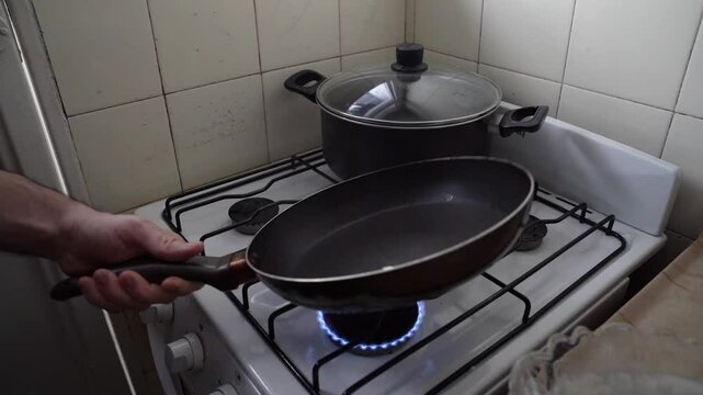 Making pancakes at home. Closeup view of a man placing butter in the hot saucepan and pouring crepe mix.