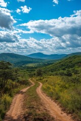 A dirt road winds through a lush green valley. The sky is cloudy, but the sun is shining through the clouds. Scene is peaceful and serene, with the beauty of nature on display