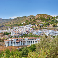 Obraz premium Nature, buildings and town for holiday, destination or travel in Andalusia with vintage architecture. Location, blue sky and ancient houses outdoor in village for vacation, getaway or trip in Spain.