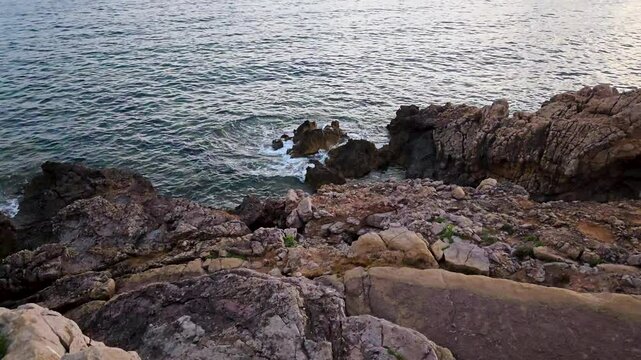 the sea waves crash on the rocks at sunset in the bay of Porto Conte
