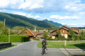 Fototapeta premium Mann steht mit deinem Fahrrad vor dem Ort Tröpolach in Nassfeld in Kärnten Österreich