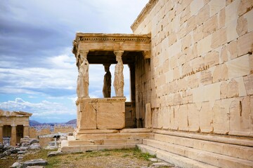 Fototapeta premium Athens, Greece, 08.26.2024: Famous marble statutes on The Porch of the Caryatids in the Erechtheum on the hill of the Acropolis of Athens in Greece, Sightseeing and vacation in Griechenland