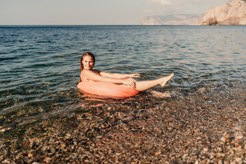 A woman is floating on a pink inflatable raft in the ocean. The water is calm and the sky is clear. The woman is enjoying her time in the water.