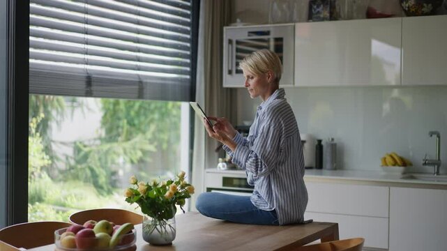 Beautiful woman adjusting smart home settings on touch screen device. Smart home technology for sustainable living.