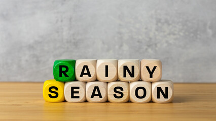 Rainy season symbol. Inscription rainy season on wooden blocks, gray background, copy space. Conceptual words, Monsoon that hits tropical countries