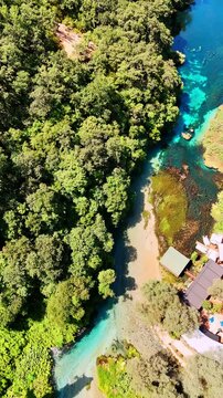 Footage above the narrow river with clear turquoise water in the mountainous area. House built on the rock in the beautiful nature. Vertical video.