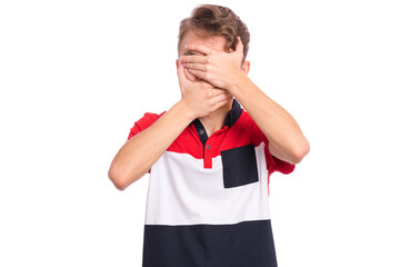 A teenage boy wearing a red and black shirt is covering his face with both hands. Isolated on white...