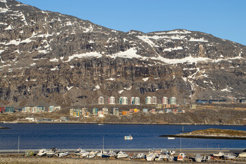 Colorful apartment buildings and boats in the harbor of Nuuk, Greenland, with snow-covered mountains in the background © O.Kobyliatskyi
