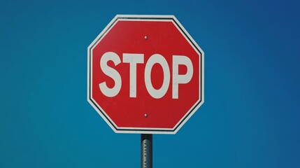 Obraz premium Red stop sign against clear blue sky, traffic safety concept