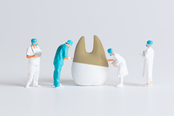 Miniature Medical Team Examining Tooth Model in Clinical Setting
