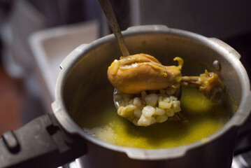 Comida Mexicana. Olla de presión con pozole verde, con cucharon metalico sacando pierna de pollo con maiz.	
