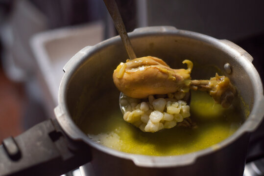 Comida Mexicana. Olla de presi&oacute;n con pozole verde, con cucharon metalico sacando pierna de pollo con maiz.	
