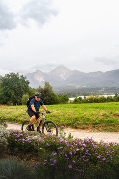 Mann f&auml;hrt mit Fahrrad am Egger Marterl mit Blick auf den Faaker See und die Berge dahinter in Villach in K&auml;rnten &Ouml;sterreich