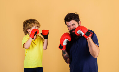 Child boy sportsman at boxing training with coach. Kid and trainer in boxing gloves ready for...