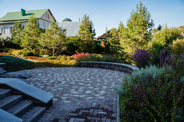 In the background, a charming house complements a beautifully maintained brick walkway in the...