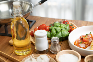 Health food's ingredients of special menu homemade cooking oil, radish, garlic, salt, oregano, basil, tomato and seasonings placing elements on preparing wooden table on blurred background. Postulate.